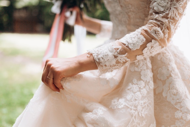details-bridal-wedding-dress-hand-with-wedding-ring-outdoors_8353-10953