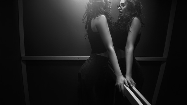 Sexy žena v čiernych šatách sa pozerá do zrkadla 